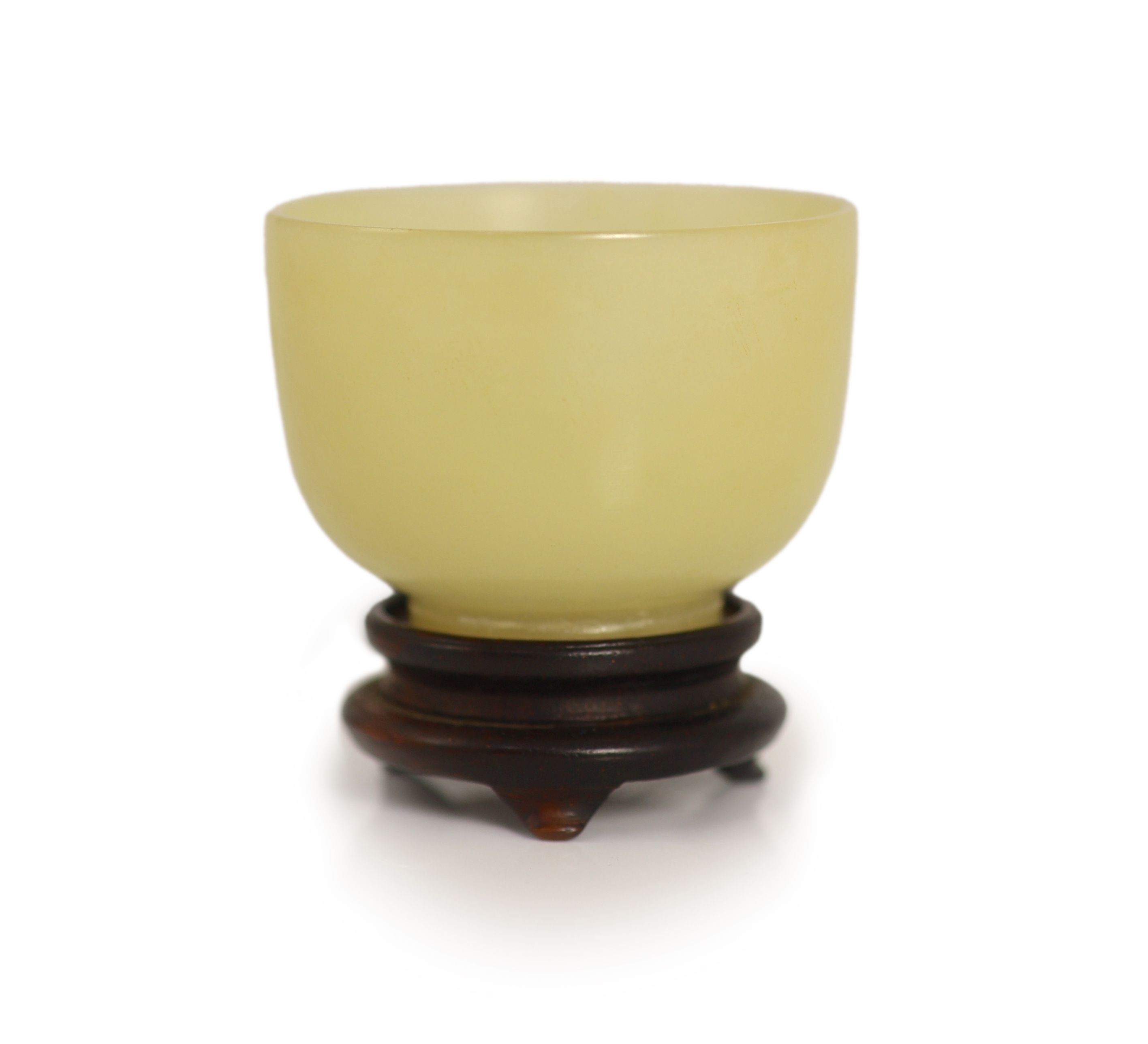 A Chinese yellow hardstone cup, 19th century, 5cm diameter, wood stand, rim chip
